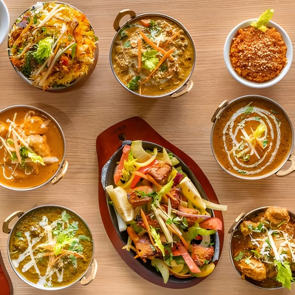 A top-down view of various Indian dishes, including curries, rice, and a sizzling platter.